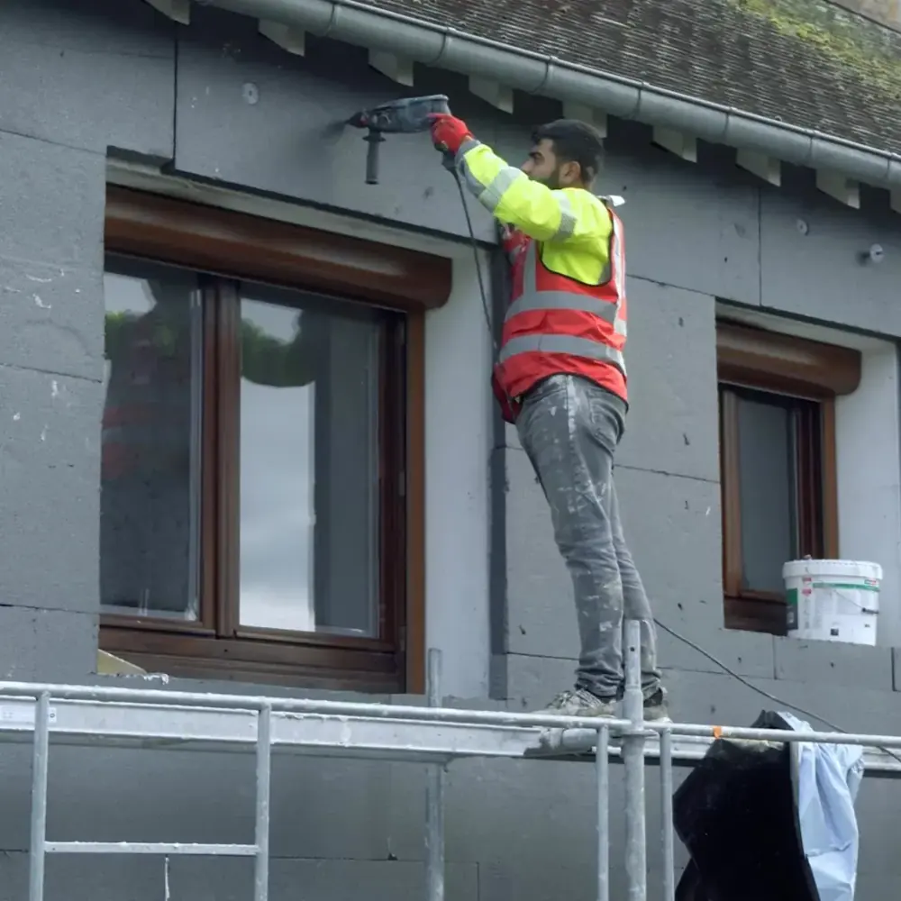 Fixation de panneaux isolants sur une façade depuis un échafaudage.