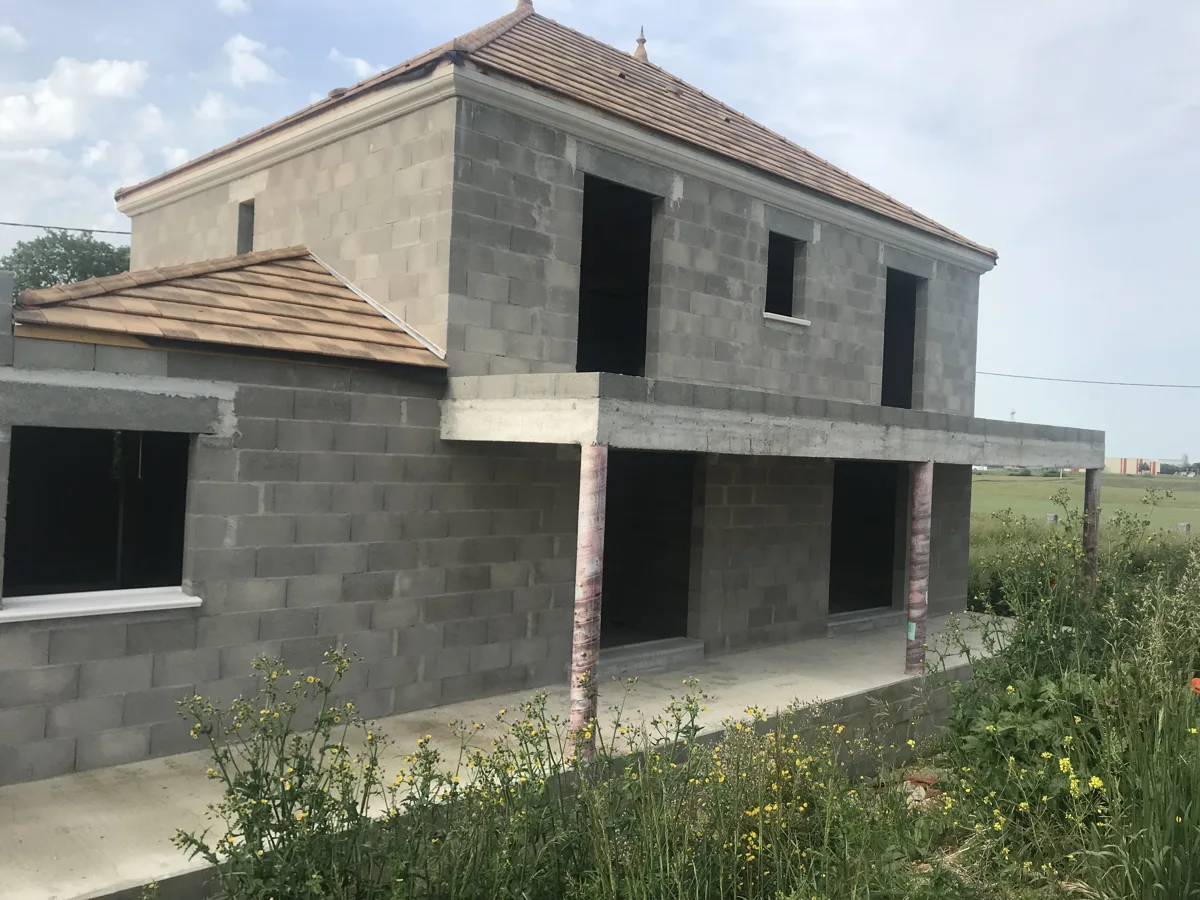 Construction maçonnée en cours : élévation des murs et volumes de la maison.