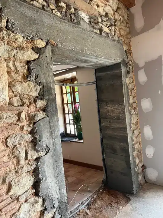 Ouverture dans un mur en pierre avec linteau en béton.